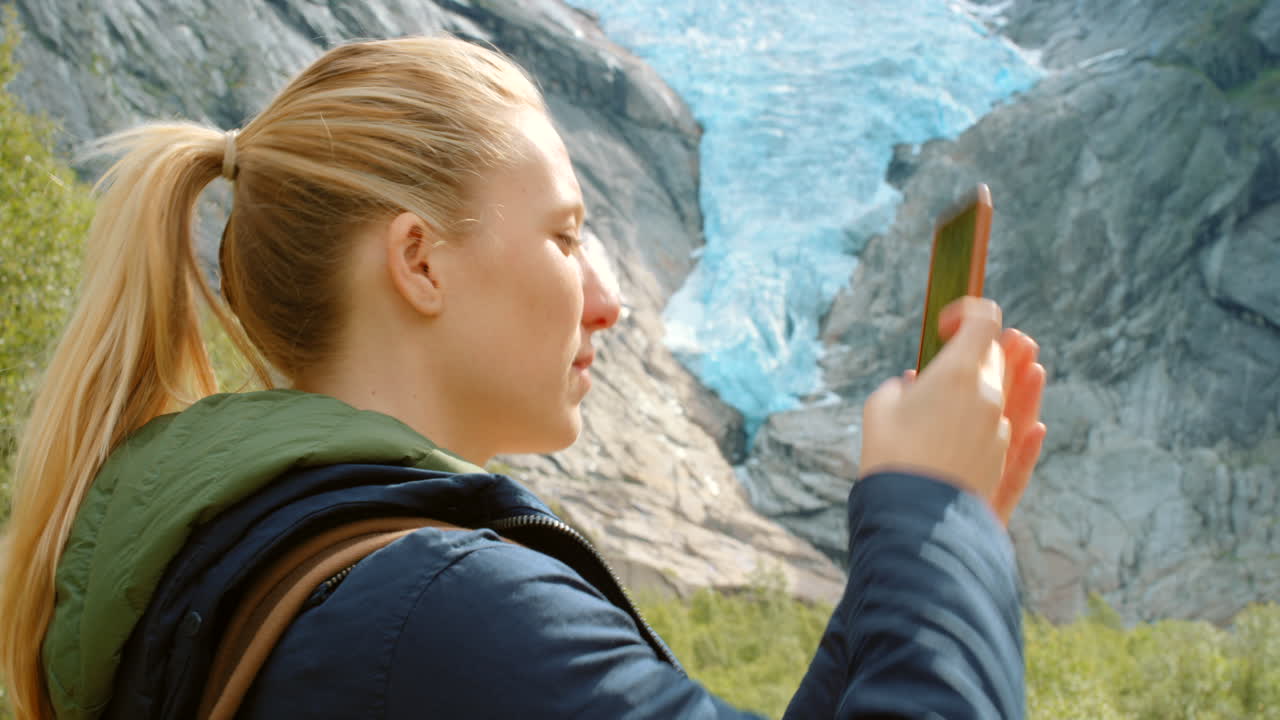 mujer tomando una foto de un glaciar