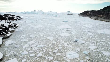 rompiendo el hielo cerca de la costa rocosa en groenlandia, vista aérea de un dron