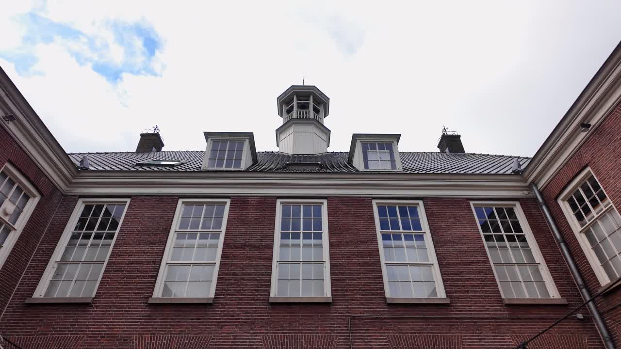 Red brick courtyard with rows of white-framed windows, partially shadowed by a large arch overhead in Ommen. Location: Ommen, Netherlands Ommen, Nederland