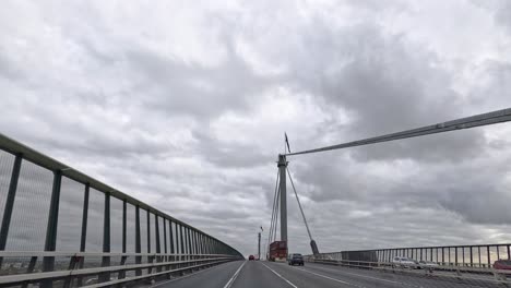 vehicles crossing a bridge under cloudy skies