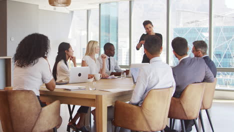 zakenvrouw staat om de vergadering rond de tafel aan te spreken