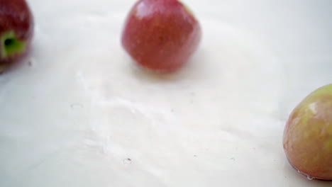 slomo of apples in water on white backdrop