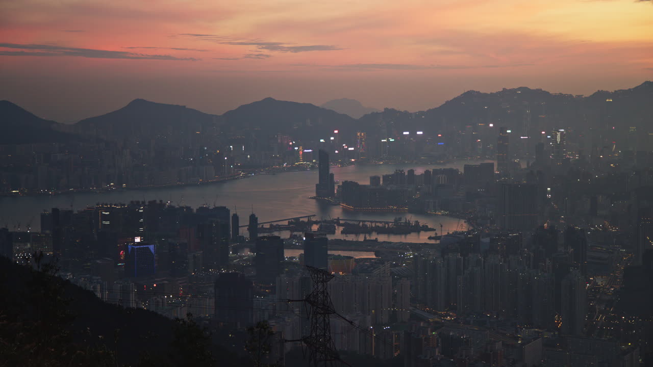 la vista captura una impresionante puesta de sol sobre hong kong, destacando el horizonte de la ciudad mientras las luces comienzan a parpadear