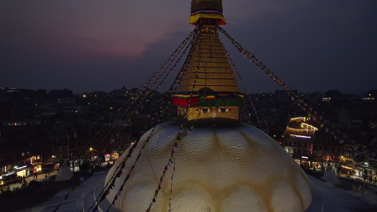A serene night drone view of Boudhanath Stupa, a UNESCO world heritage site. The sacred Buddhist landmark glows beautifully above Kathmandu’s peaceful evening skyline