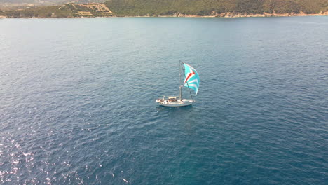 Sail-Boat-Sailing-in-Mediterranean-Sea-by-a-Coastline-of-Sardinia-Island,-Italy