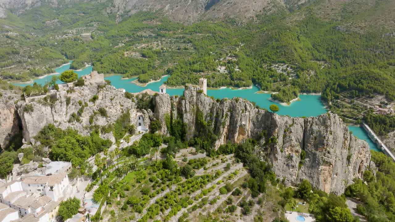 Aerial view of a village nestled in a valley with a reservoir and mountain background