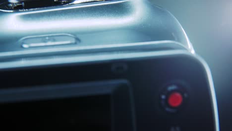 a macro close up shot of a video camera, silver camcorder on a 360 rotating stand, studio lighting, slow motion 4k video, open flipped screen, record and menu buttons