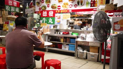 man dining at a bustling street food stall