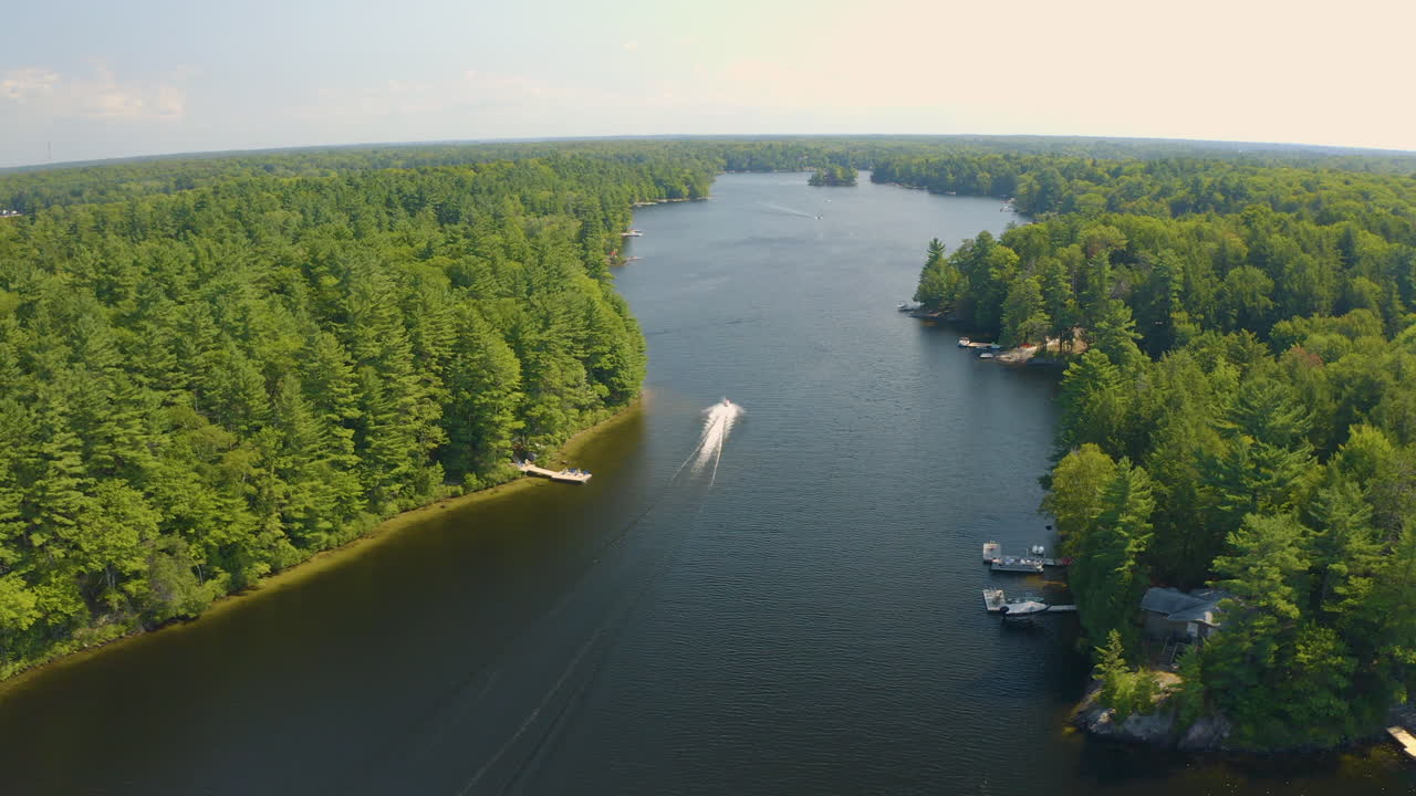 Vista drone di una moto d'acqua che si allontana lungo un fiume, lontano dalla telecamera, in una bella giornata estiva