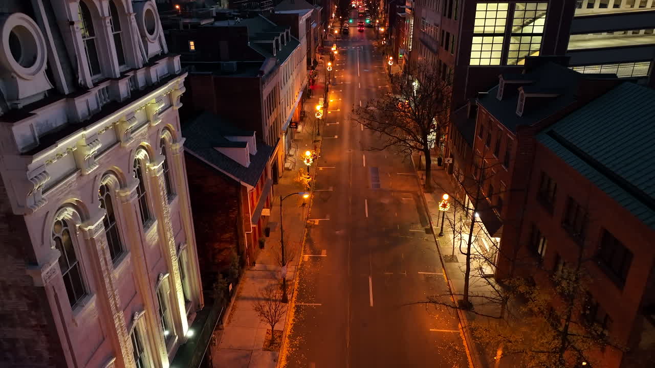 Christmas wreath decoration on lamp posts in urban city. Car traffic at night. Rising aerial.