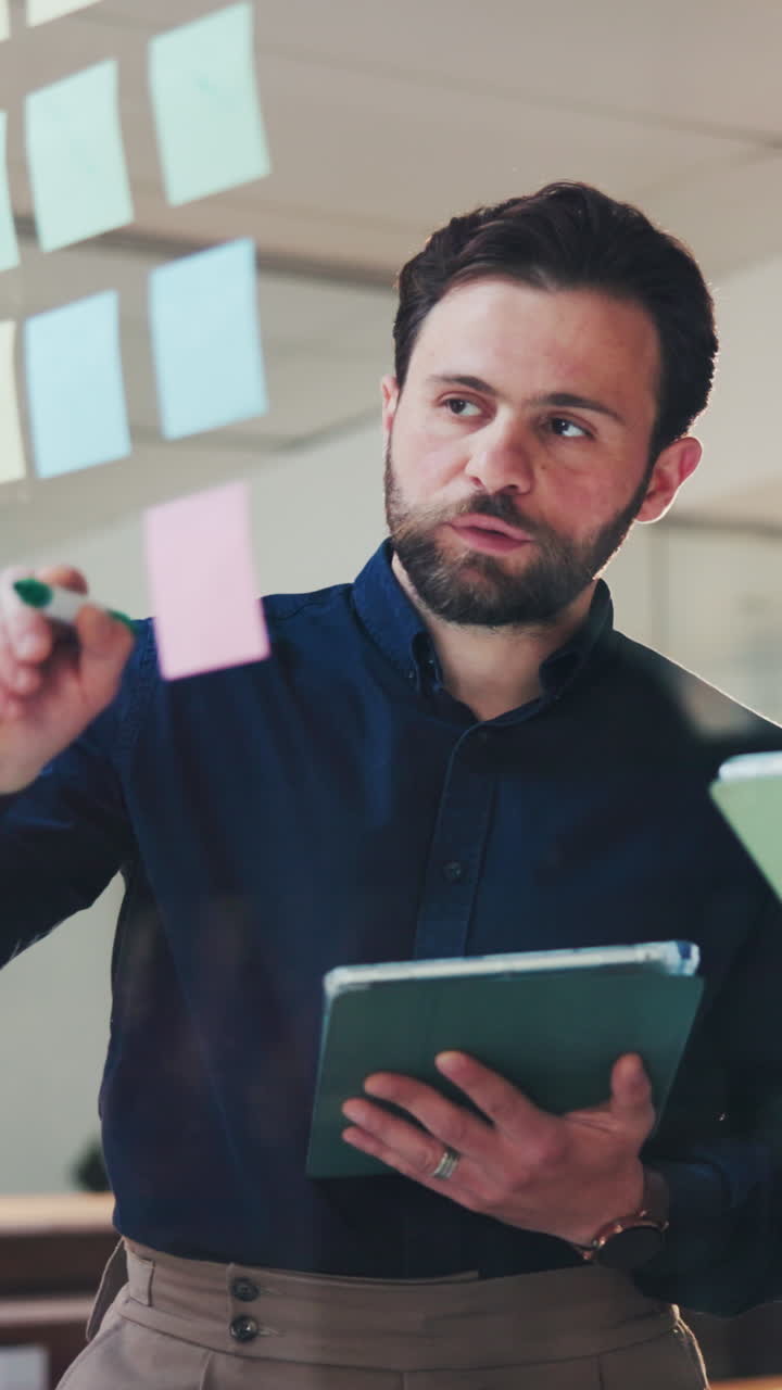 Man Writing on Sticky Note During Brainstorming Session in Office