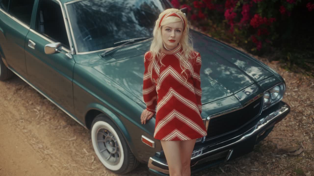 Mujer elegante con vestido retro posando con coche clásico