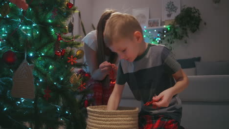 Der-Junge-Wählt-Glaskugeln-Für-Seine-Mutter-Aus,-Um-Den-Weihnachtsbaum-Zu-Schmücken.-Familie-Schmückt-Gemeinsam-Ihr-Zuhause-Zu-Weihnachten.-Hochwertiges-4K-Filmmaterial