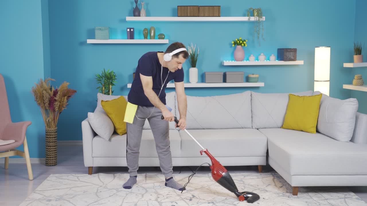 그 남자는 집을 청소하고 있는데 갑자기 그의  ⁇ 자루를 마이크로 바꾸고 노래를 부르고 있습니다.