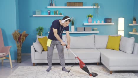 the man is cleaning his house and all of a sudden he is using his broom into a microphone and singing.