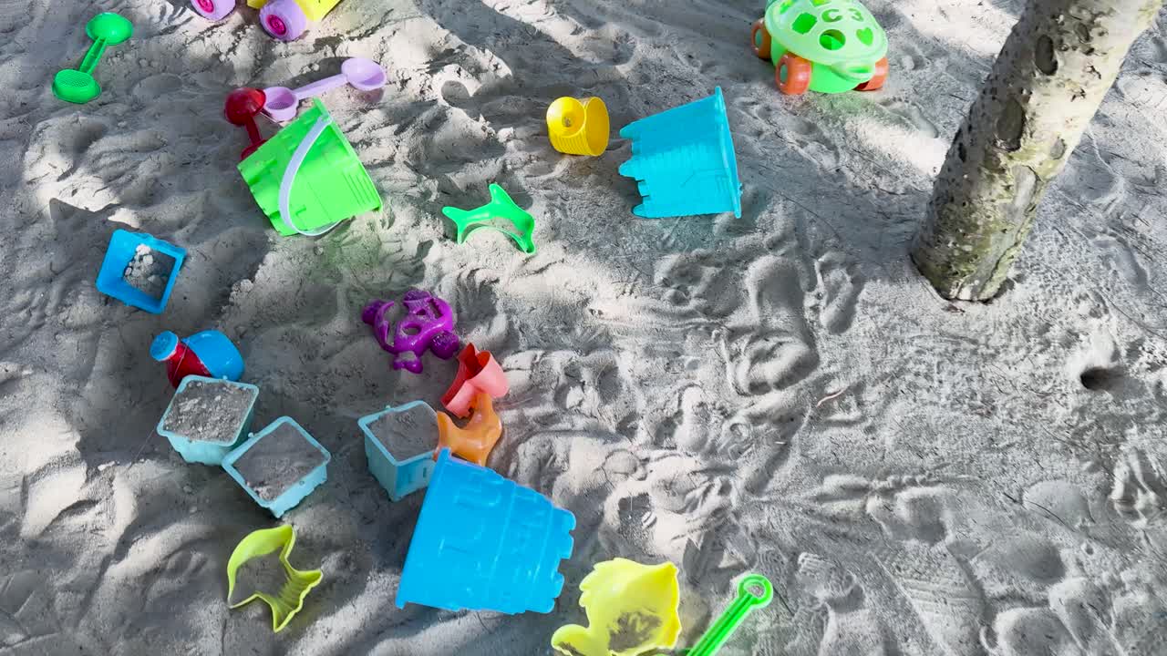 태국 푸켓의 빛이 비치는 모래 해변에 어져있는 플라스틱 장난감. 밝은 색과 유쾌한 배열은 즐거운 분위기를 만니다.