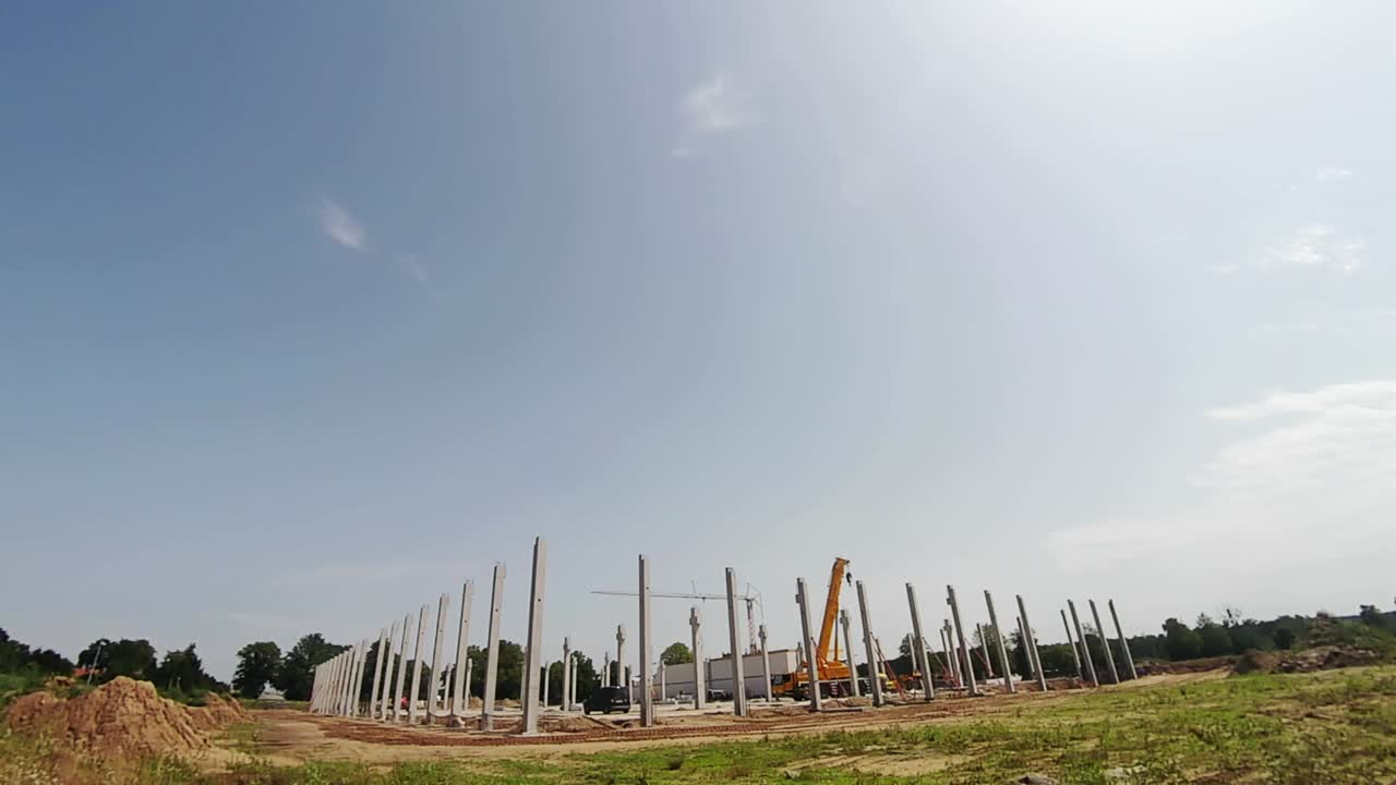 una grúa de construcción está colocando pilares de hormigón contra el fondo del cielo