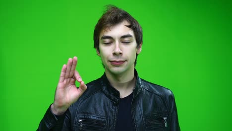 white man in leather jacket showing approval or ok sign on green screen background.