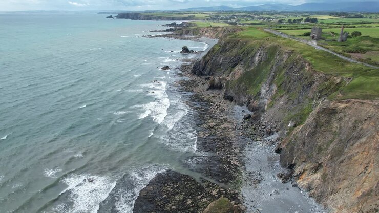 Tankardstown Copper Coast Waterford İrlanda'da rüzgarlı bir Temmuz gününde, şiddetli yağmurdan hemen önce deniz kayalıkları ve plaj boyunca drone uçuşu.