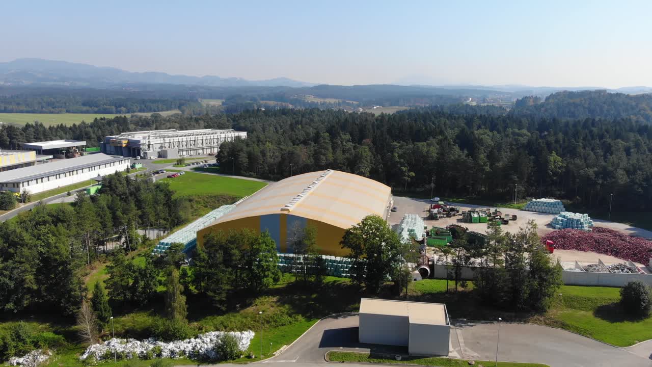 Waste recycling plant specializing in plastics and rubber with loader machine operating, Aerial turn right shot