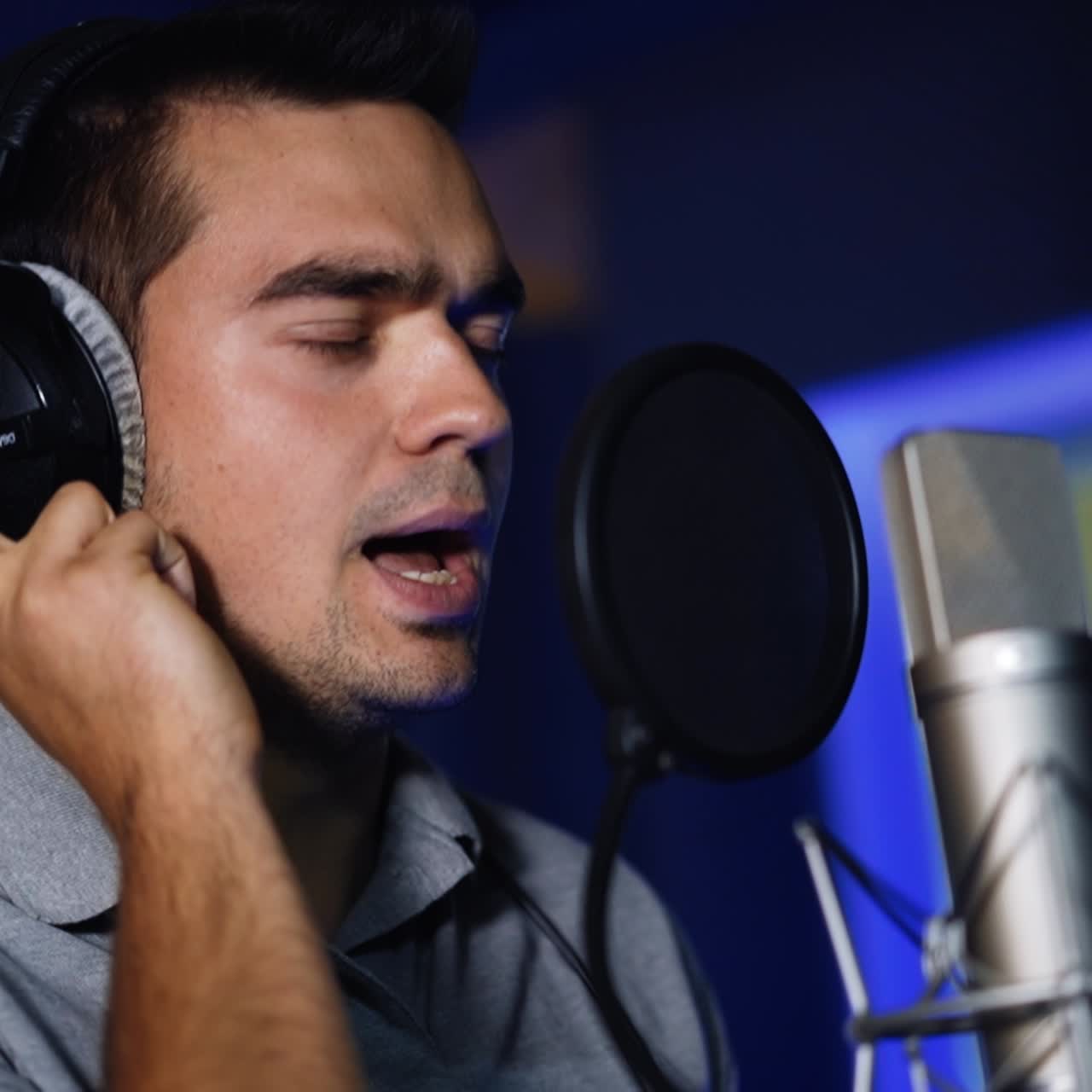 Cantante emozionato che interpreta una canzone in uno studio buio. Registrazione di una canzone in un moderno studio di registrazione professionale.