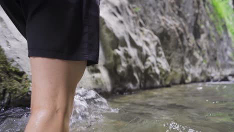 close-up of man's feet walking in the creek.