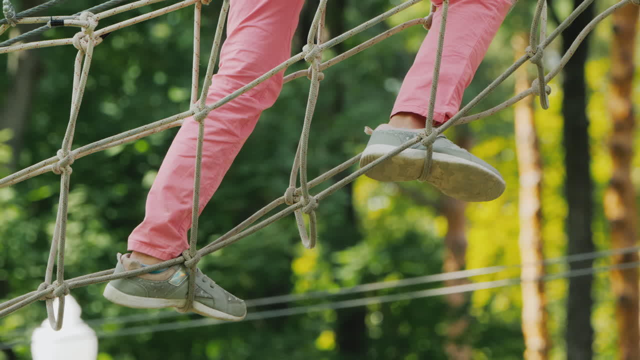 나무 사이에 뻗은 케이블을 따라 걷는 아프리카계 미국인 어린이의 발