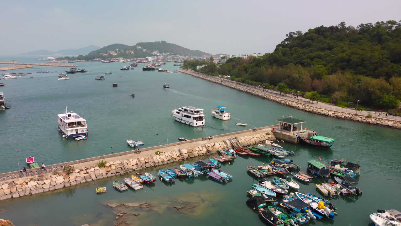Drone Orbit Tracking Pier reveal Mountain from far. HD 4k footage of Cheung Chau Island, Hong Kong, fishing village yacht pier.