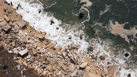 Aerial-top-down-shot-of-rocks-at-shore-and-crashing-waves-of-Atlantic-ocean-at-sunny-day,-Portugal---circling-shot