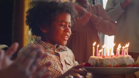 happy african american kid blowing candles on birthday cake