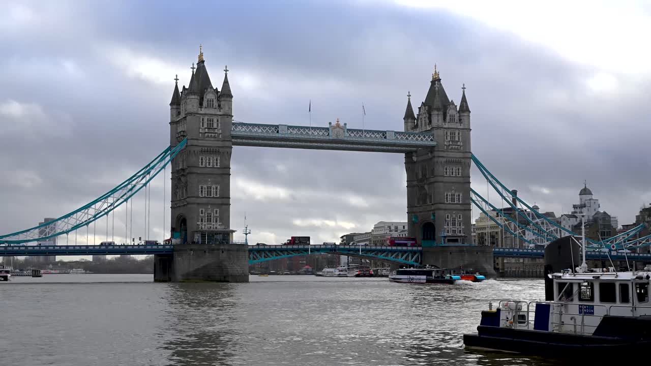 De ikoniske victorianske gotiske tårne på Tower Bridge set fra den historiske stenpromenade ved Tower of London-fæstningen med udsigt over Themsen om natten