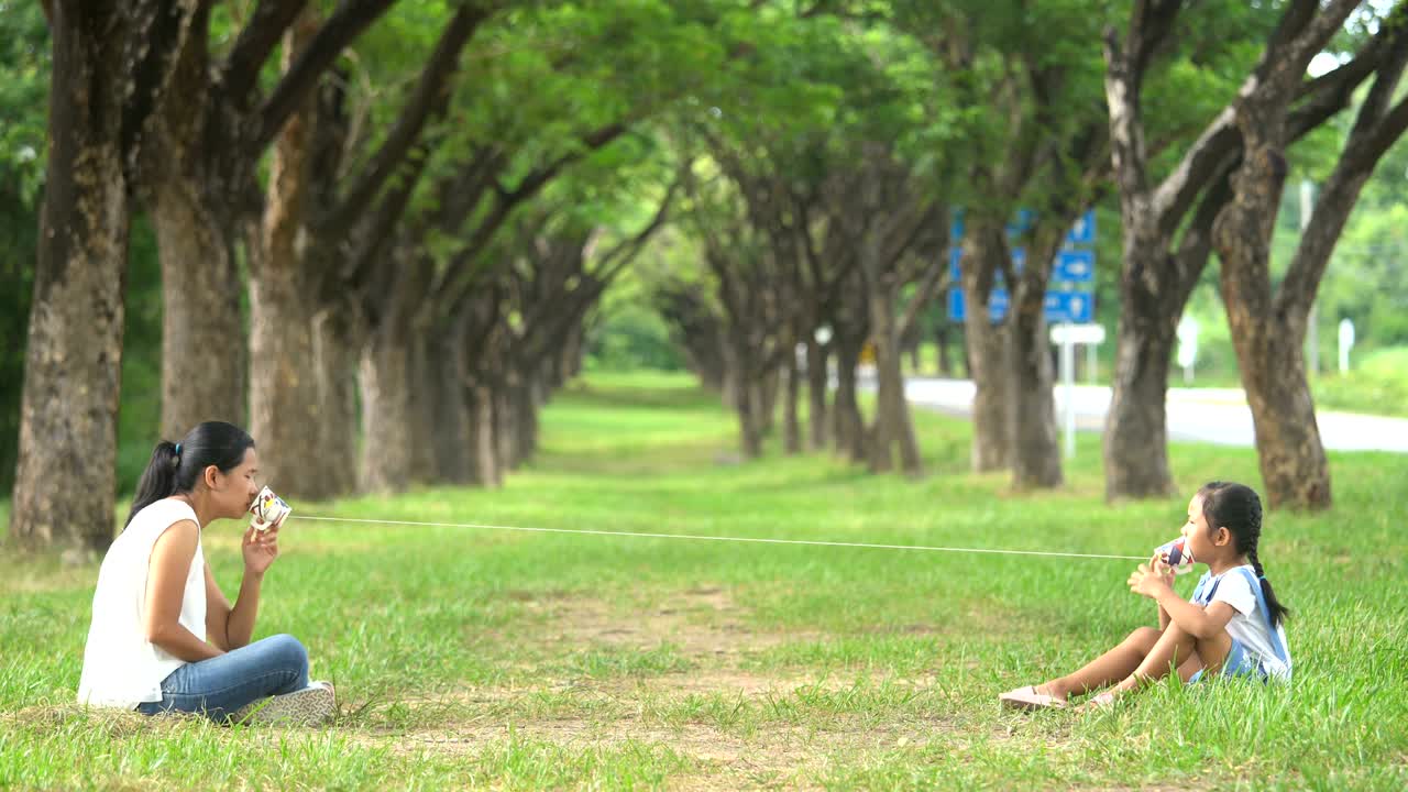 아시아 가족, 어머니와 딸이 공원에서 줄을 는 스트링 폰 놀이 활동을 하고 있습니다.