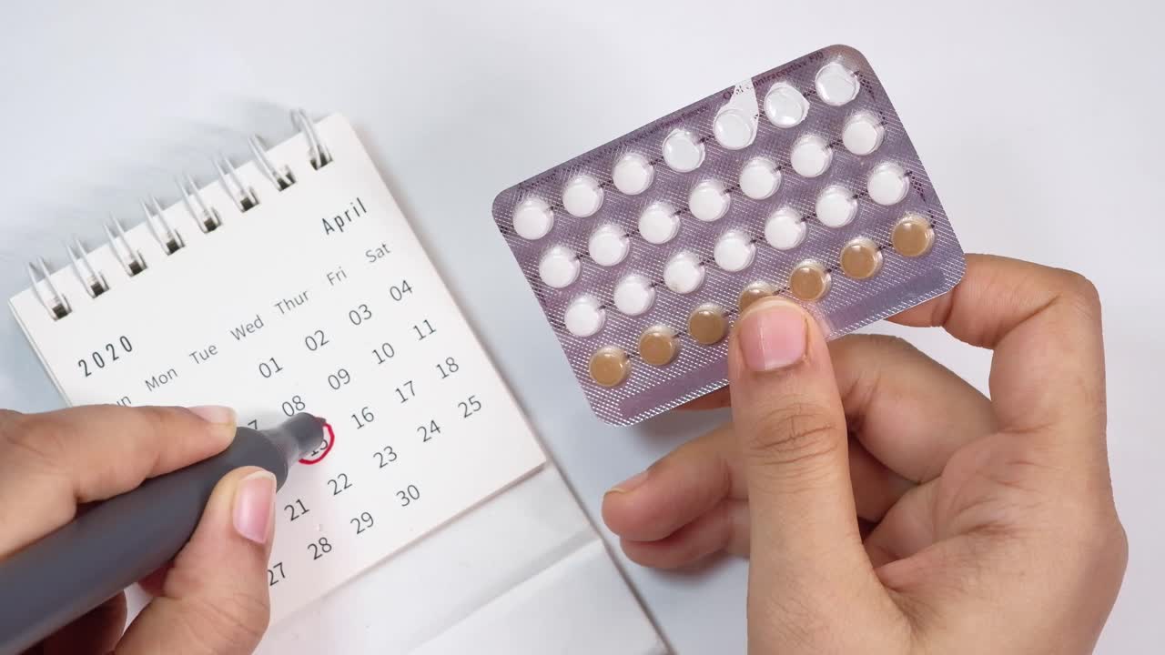 Mujer tomando píldoras anticonceptivas y marcando el calendario