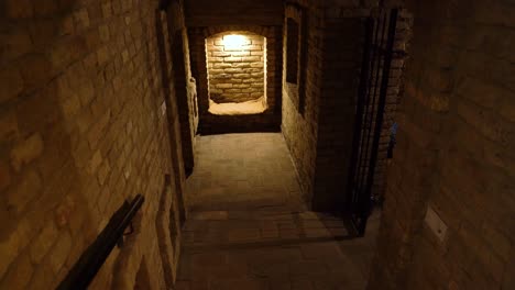 dimly lit brick wine cellar corridor with an arched alcove and soft lighting