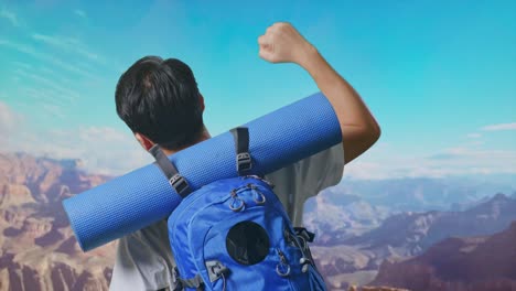 close up back view of a male hiker with mountaineering backpack screaming goal celebrating the success while traveling at the top of mountain