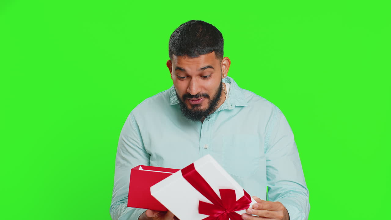 남자가 빨간 리본으로 생일 선물 상자를 열고, 큰 선물 놀라움을 받고, 축하합니다.