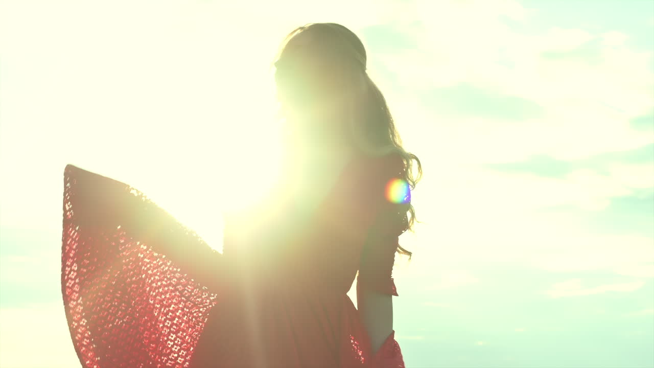 A young woman enjoys the sunlight as she smiles softly, surrounded by open skies and natural light