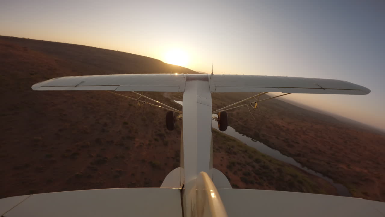 Aereo leggero che sorvola un fiume nella savana al tramonto