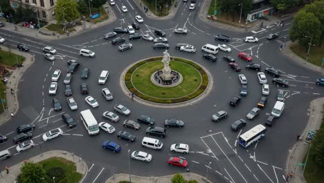 aerial view of traffic flowing around a central roundabout with a statue surrounded by vehicles in various directions, highlighting urban transportation dynamics
