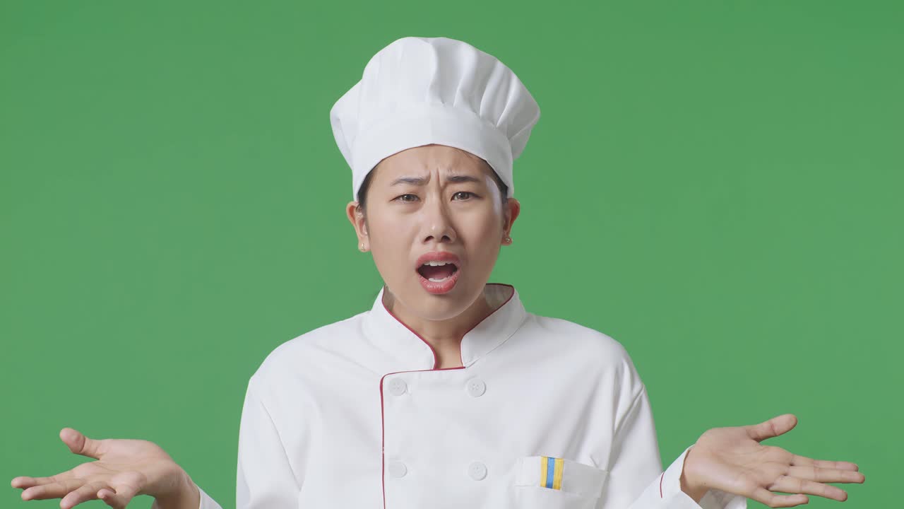 Close Up Of Wondering Asian Woman Chef Saying Why And Standing Doubtfully In The Green Screen Background Studio