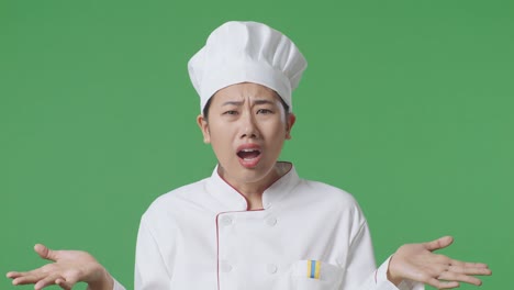 close up of wondering asian woman chef saying why and standing doubtfully in the green screen background studio