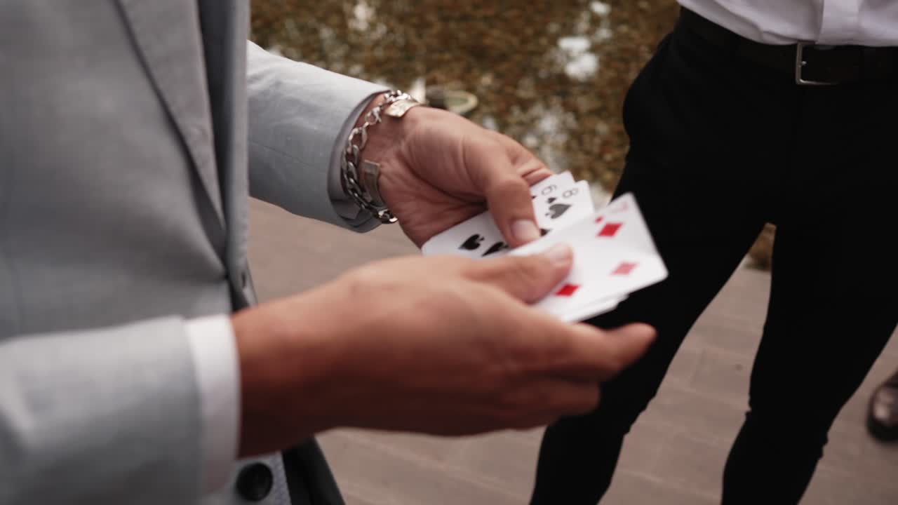 Close up of a magician's hands performing a card trick in an outdoor setting
