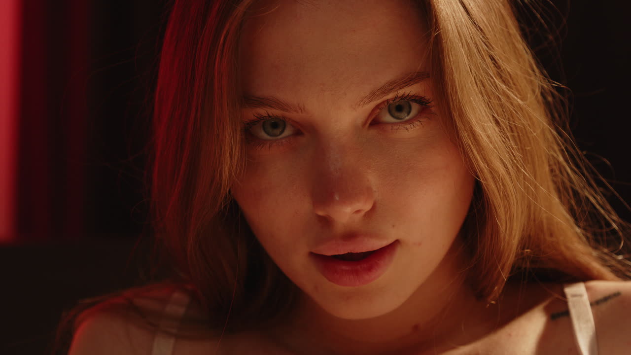 Stunning portrait of an attractive Caucasian woman sensually gazing at the camera with her bright blue eyes in slow motion