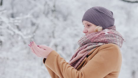 attractive woman catches snowflakes in her palms enjoys beautiful winter day