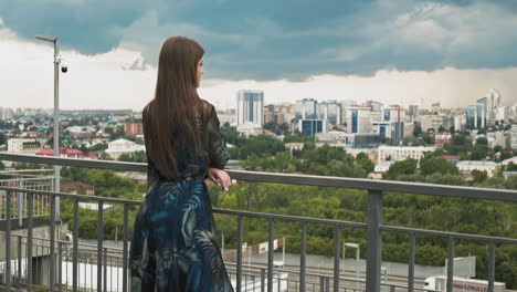 lady leans on handrail on viewing deck against large city