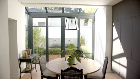 dining room with round table and chairs, sunlight streaming through large windows, copy space
