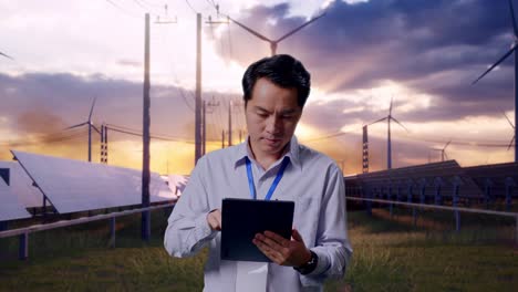asian male professional worker standing with his tablet with solar panel and wind turbines, work continuously with his tablet
