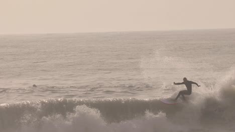 hombre surfista surfea la ola en el océano y hace un enorme flotador en cámara lenta