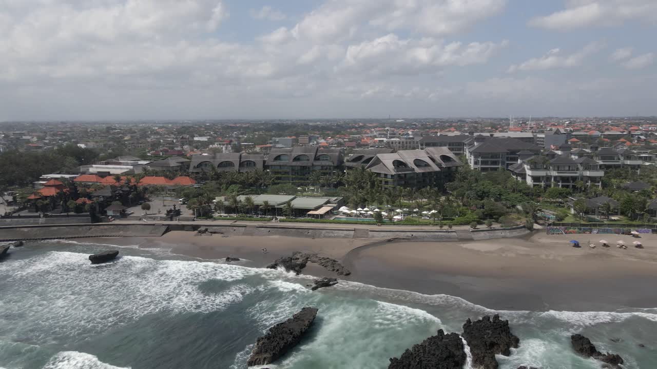 panorámica aérea a través del club de playa de como en la orilla de la playa de canggu, bali