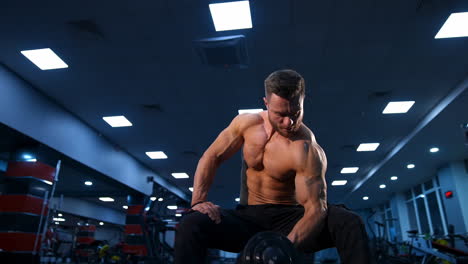 handsome power athletic man bodybuilder doing exercises with dumbbells. fitness muscular body on dark gym background. slow motion.